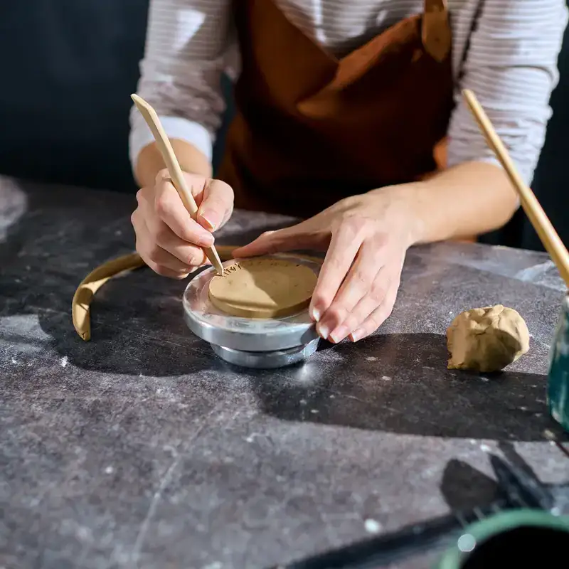 Persona che lavora l'argilla con strumenti da ceramica