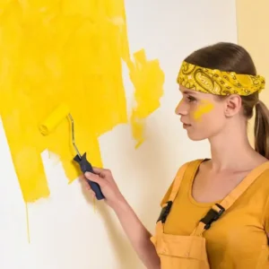 Ragazza che dipinge una parete con vernice ecologica gialla